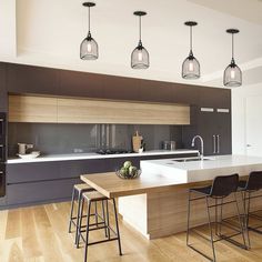 a kitchen with an island and four lights hanging from the ceiling