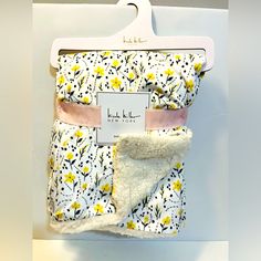 a white and yellow flowered blanket hanging on a wall next to a tag with the name new york