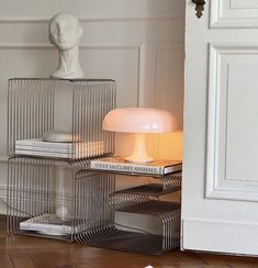 a stack of books sitting on top of a wooden floor next to a white lamp