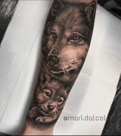 a man with a wolf tattoo on his arm next to an adult wolf and cub