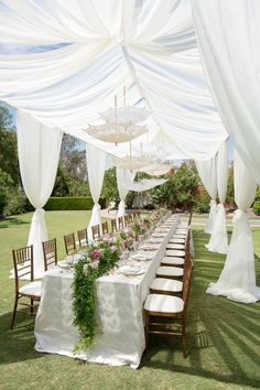 a long table with white draping and flowers on it