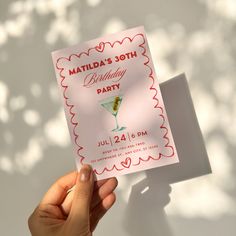 someone holding up a birthday party card with a martini in the glass on it's side