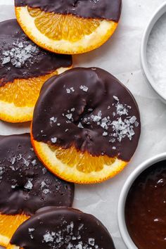 chocolate covered orange slices are arranged on top of each other, with dipping sauces nearby