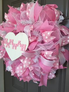 a pink and white wreath that says happy on the front door with a heart hanging from it