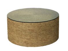 a round coffee table with a glass top and jute material on the bottom, against a white background