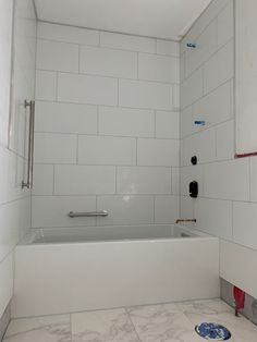 a white tiled bathroom with a bathtub and shower