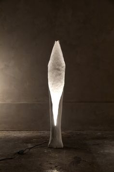 a large white sculpture sitting on top of a floor next to a light that is turned on