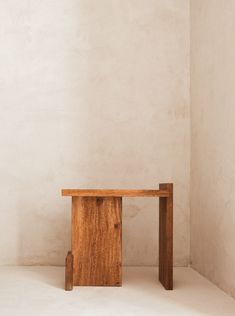 a wooden table sitting in the middle of a room next to a white wall and floor