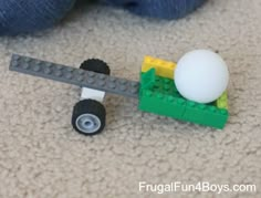 a lego toy is laying on the floor next to a ball and wheelbarrow