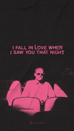 a man sitting on top of a couch in front of a pink poster with the words i fall in love when i saw you that night