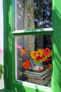 a vase with flowers sitting on top of a window sill next to a stack of books