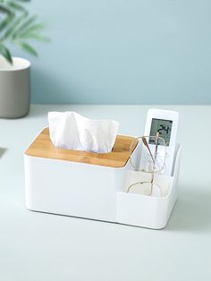 a tissue dispenser sitting on top of a table next to a plant