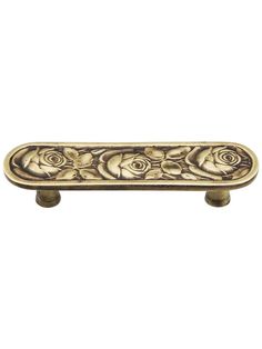 an antique brass cabinet handle with roses on the front and bottom, against a white background