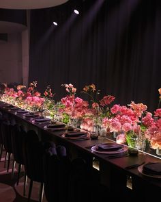 a long table with many vases filled with pink flowers on top of each one