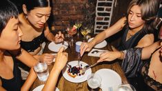 three women sitting at a table with plates of food and drinks in front of them