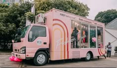 a pink food truck parked in front of a building