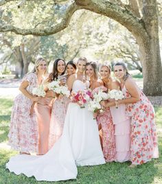 a group of women standing next to each other in front of a tree with flowers