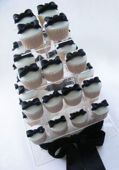 cupcakes are arranged in the shape of a pyramid with black bows on them