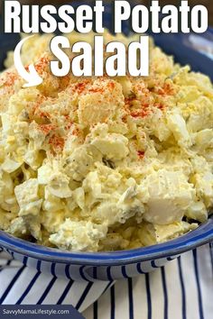 a blue bowl filled with potato salad on top of a white and blue striped table cloth