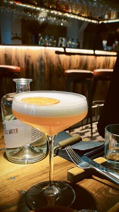 a glass filled with liquid sitting on top of a wooden table