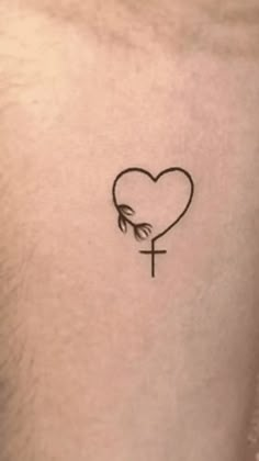 a small cross and heart tattoo on the chest