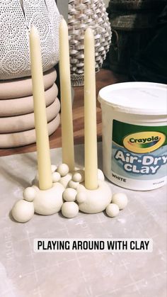 some candles sitting on top of a table next to white rocks and a can of paint