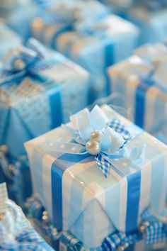 blue and white gift boxes with bows and pearls on them, all wrapped in ribbon