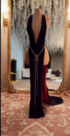 a mannequin wearing a black dress in front of a mirror with chains on it