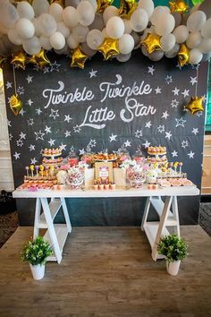 a table topped with lots of desserts and balloons in front of a chalkboard