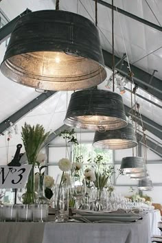 several lights hanging from the ceiling above a table with flowers and wine glasses on it