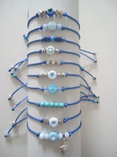 a christmas tree made out of bracelets and beads on a white wall with blue string