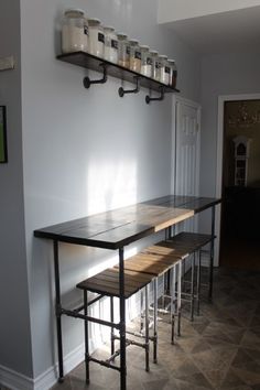 a long table with two stools in front of it and some shelves on the wall