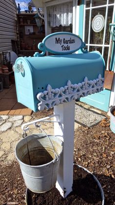 a blue mailbox sitting on top of a tree stump next to a bucket filled with dirt