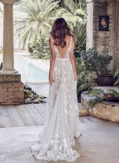 a woman in a wedding dress is standing near an archway and looking at the pool