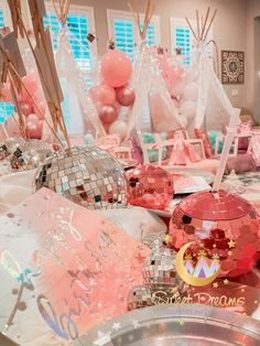 pink and silver decorations are on display in a room filled with balloons, streamers and disco balls