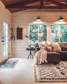 a living room with couches, rugs and two lamps on the ceiling in front of windows