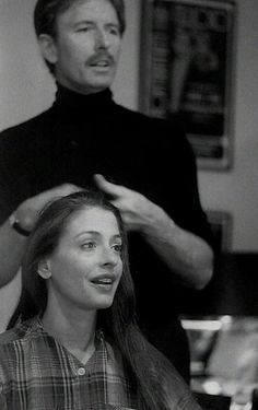 a man standing next to a woman who is blow drying her hair