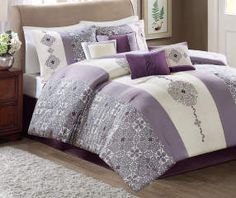 a bed with purple and white comforters in a room