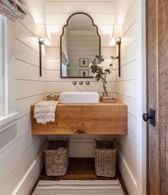 a bathroom with a sink, mirror and two wicker baskets on the floor in front of it