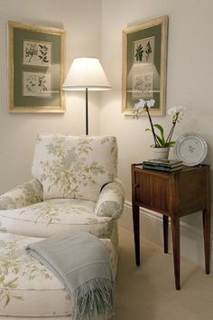 a chair and ottoman in a room with two pictures on the wall behind it,