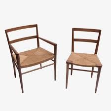 two wooden chairs with woven seat cushions on each side and one chair in the middle