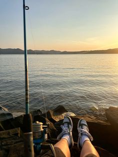 someone is sitting on the rocks with their feet up and fishing