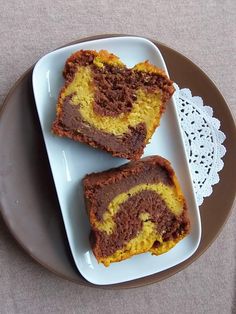 two pieces of chocolate and yellow swirled cake on a plate next to a lace doily