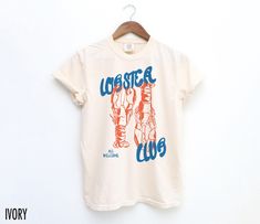 Embrace coastal charm with this vintage-inspired tee! Featuring a hand-drawn lobster graphic and the phrase "Lobster Club, All Welcome," this shirt brings a touch of retro style to your everyday look. We use professional quality DGT printing on all our apparel. Direct-to-garment, or DTG, is a high quality printing method that sprays ink directly onto the garment so there is no peeling or cracking. This fabulous graphic will be printed on a Comfort Colors Unisex T-Shirt. Please refer to the size Food Graphic Tee, Lobster Graphic, Lobster Shirt, Aesthetic Coastal, Vintage Diner, Food Shirt, Crawfish Boil, Coastal Charm, Aesthetic T Shirts