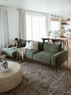 a person sitting on a couch in a living room next to a table with a laptop