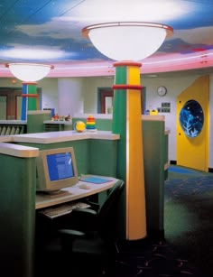 a computer desk with a laptop on top of it next to a yellow and green lamp