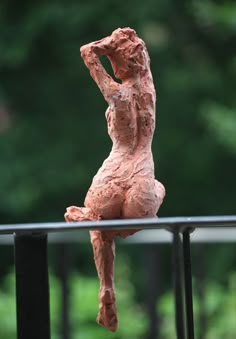 a clay sculpture sitting on top of a metal rail