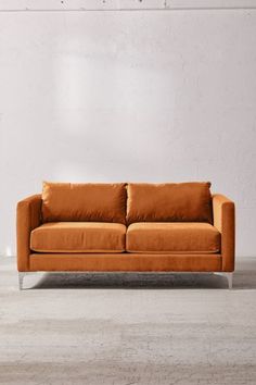 an orange couch sitting in front of a white wall