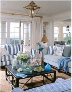 a living room filled with blue and white striped couches next to a window covered in curtains