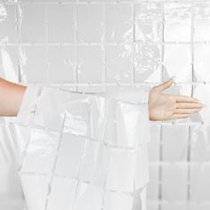 a woman with her arm wrapped around a white plastic bag in front of a tiled wall